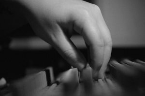 A black-and-white image featuring a close-up of a hand delicately adjusting the keys of an audio mixing console, accompanied by the text 'Quator Foot Locker' in an elegant font, evoking precision and artistry